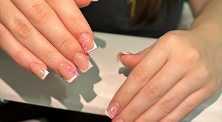 Elegant French manicure with pink floral design at Belsbeautybarx, Birmingham, England, GB.