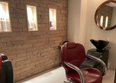 Interior elegante de N&H Vital Hair en Chihuahua, Chihuahua, MX con sillas de salón y productos iluminados.
