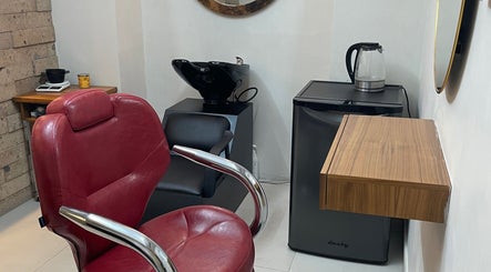 Silla de salón roja en N&H Vital Hair, Chihuahua, Chihuahua, MX, junto a un lavamanos y una pequeña nevera.