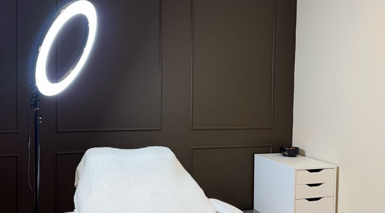 Cozy treatment room at LASHEDBYKIRA, Cefn-mawr, Wales, GB, featuring a lighted ring and plush seating.