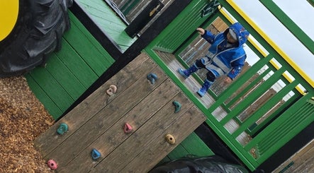 Child exploring outdoor play area at BeYouBeauty, Larne, Northern Ireland, GB on a green playground structure.