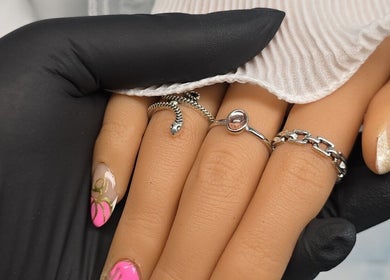 Intricate nail art at BeYouBeauty, Larne, Northern Ireland, GB. Black-gloved hand holds manicured fingers.