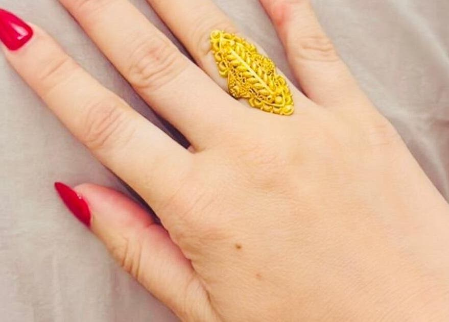 Elegantly manicured hand with red nails and gold ring at Glow Up, Cape Town, Western Cape, ZA.