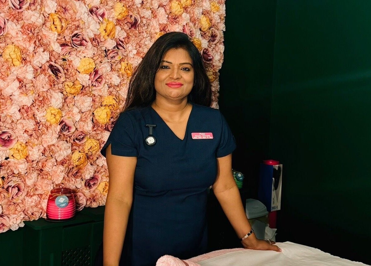 Therapist at Pinks Beauty & Spa, Hitchin, England, GB, stands before a floral wall, enhancing the serene ambiance.