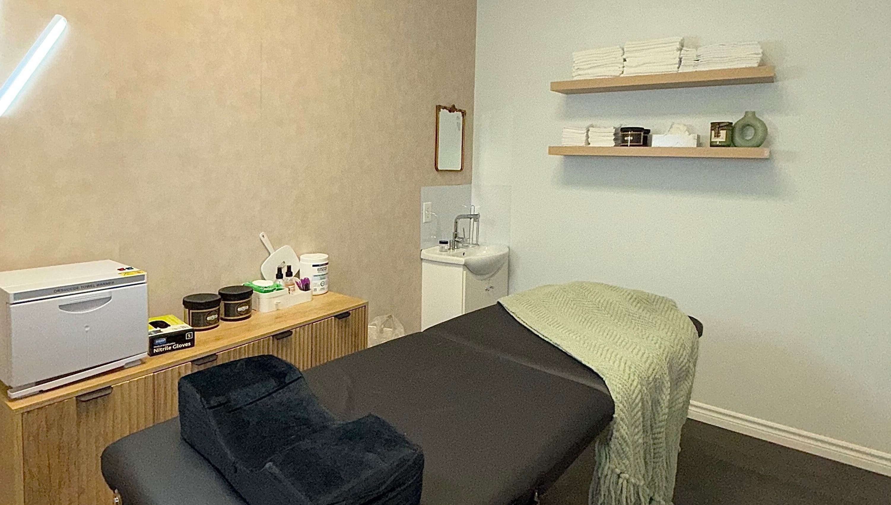 Treatment room at Skin Glow Studio x Sugar & Skin, London, Ontario, CA featuring a massage table and elegant decor.