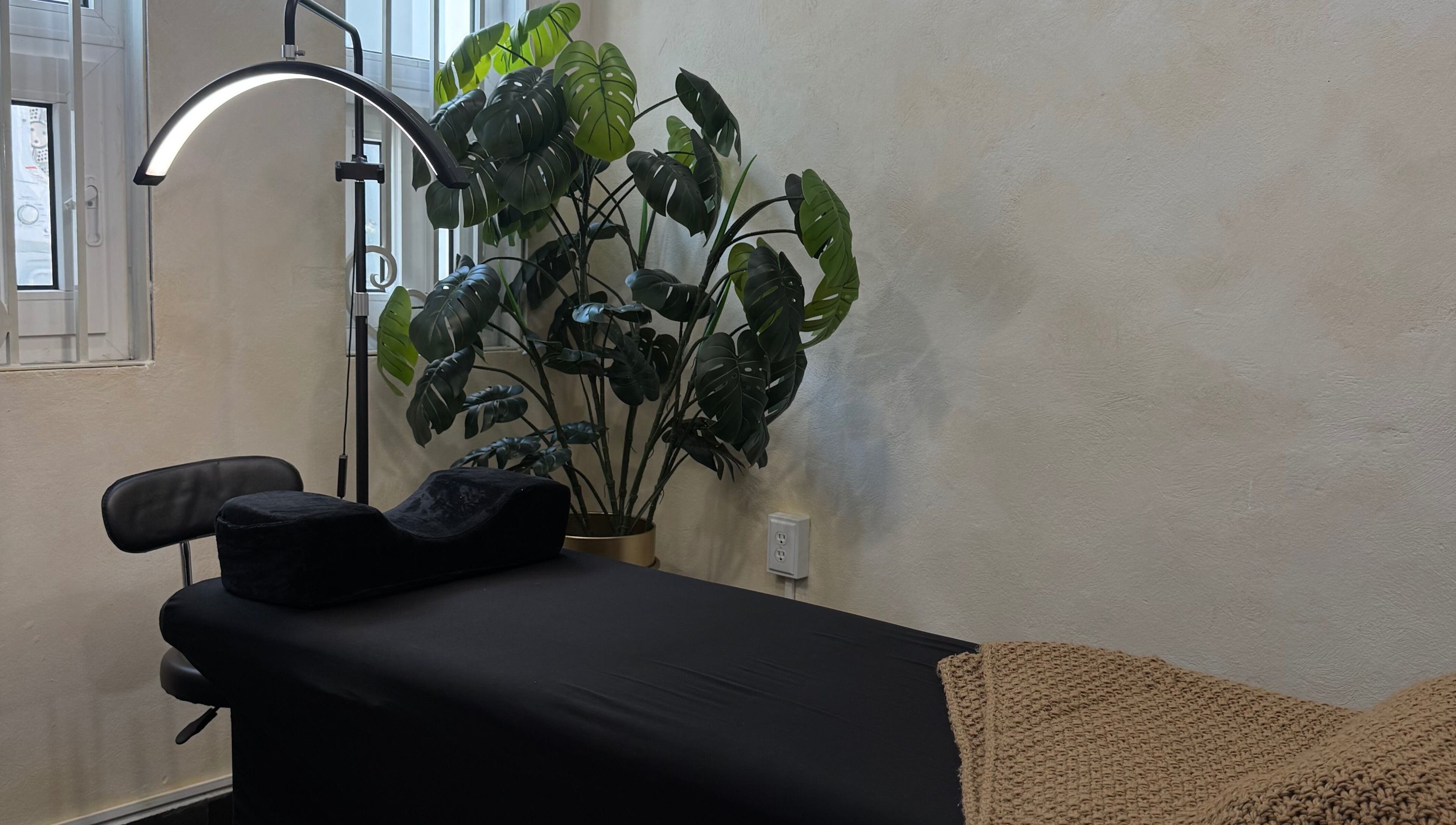 Relaxing massage room at GLOSSBEAUTY SALÓN, Tampico, Tamaulipas, MX with black bed and green plant decor.
