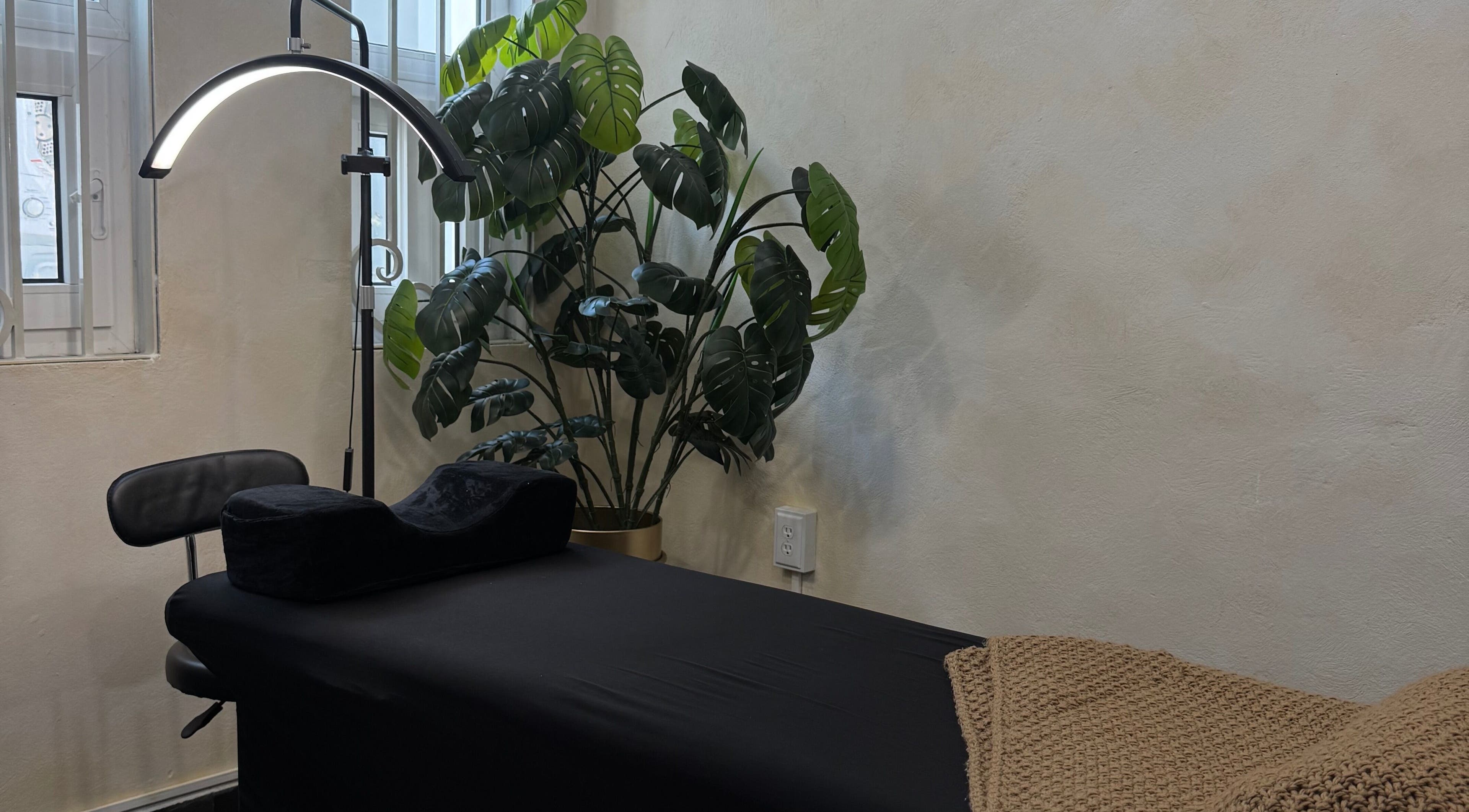 Relaxing massage room at GLOSSBEAUTY SALÓN, Tampico, Tamaulipas, MX with black bed and green plant decor.