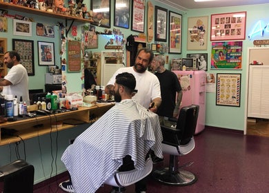 Interior of Dans Traditional Barbershop in Auckland, NZ, showing a barber styling a customer's hair.