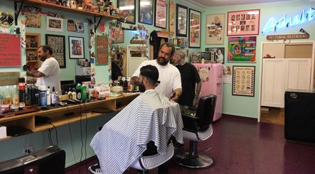 Interior of Dans Traditional Barbershop in Auckland, NZ, showing a barber styling a customer's hair.