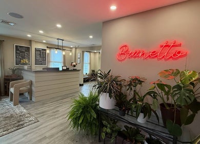 Inviting reception of Brunetto Beauty in Oakland, New Jersey, US with plants and a neon sign.