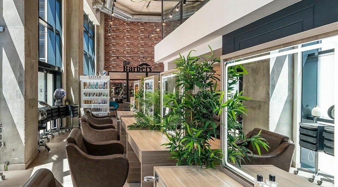 Modern interior of Studio 44 On Madison in Gibraltar, GI featuring stylish barber chairs and lush greenery.