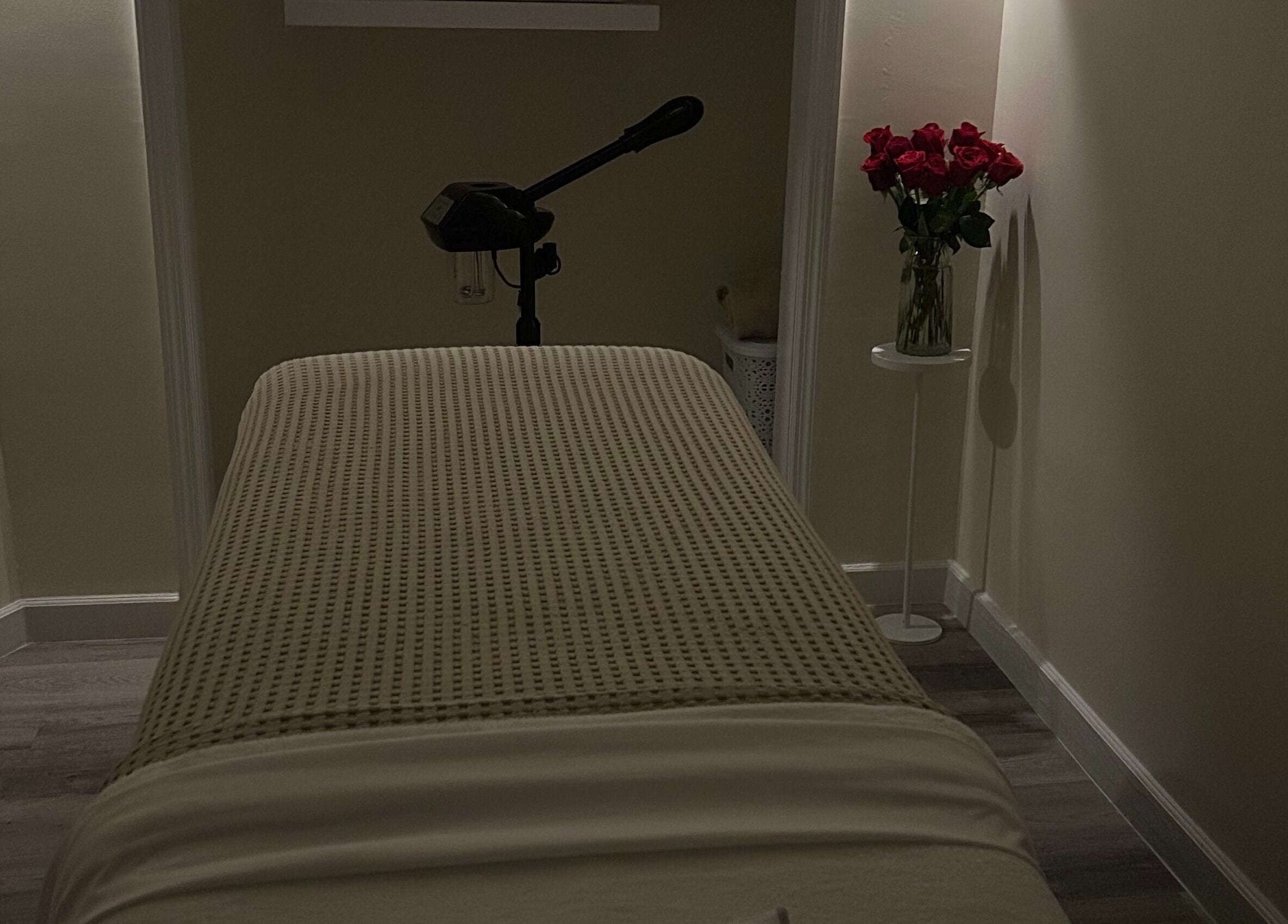 Peaceful treatment room at Skin Knead Beauty, Nassau, New Providence, BS with table and roses.