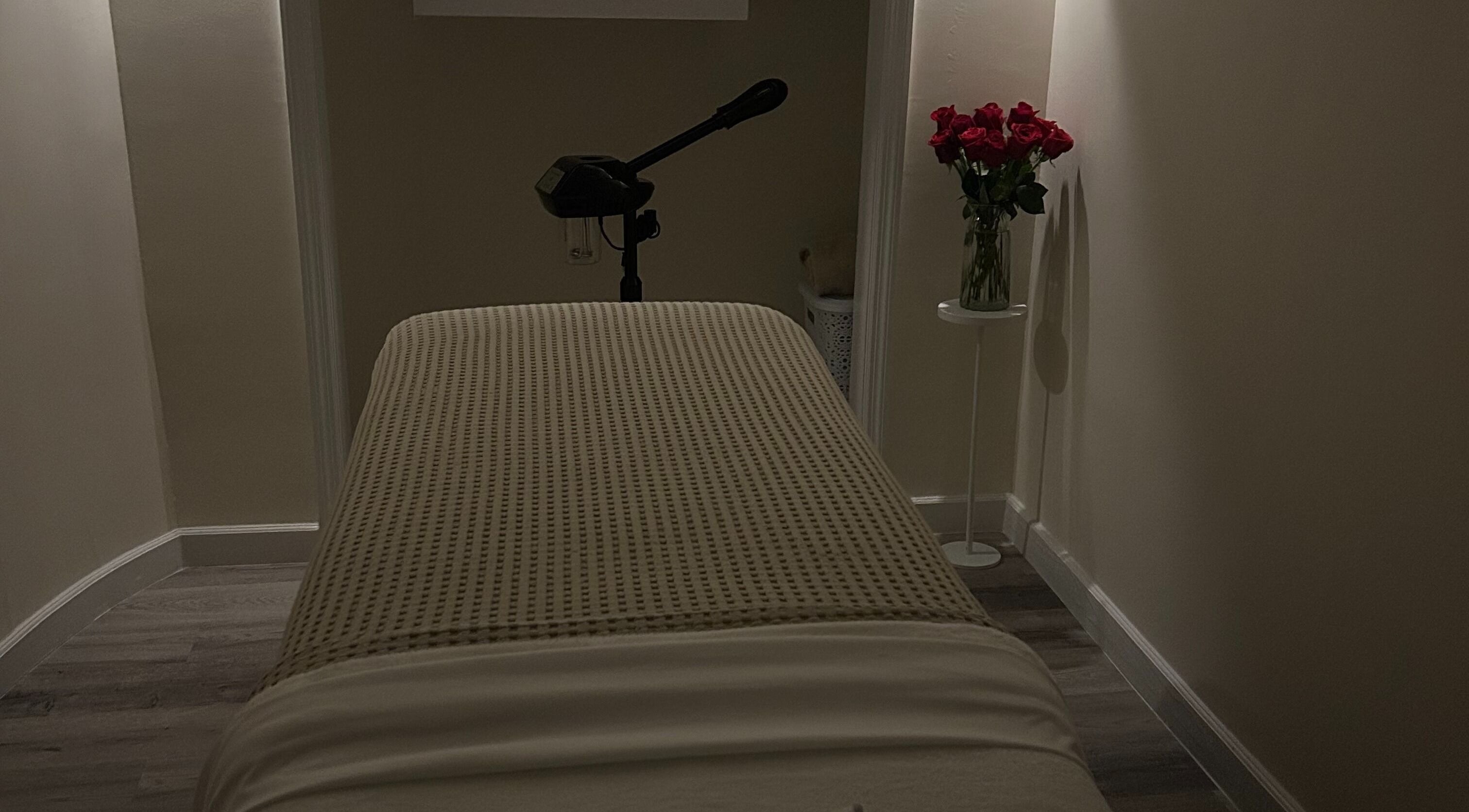 Peaceful treatment room at Skin Knead Beauty, Nassau, New Providence, BS with table and roses.