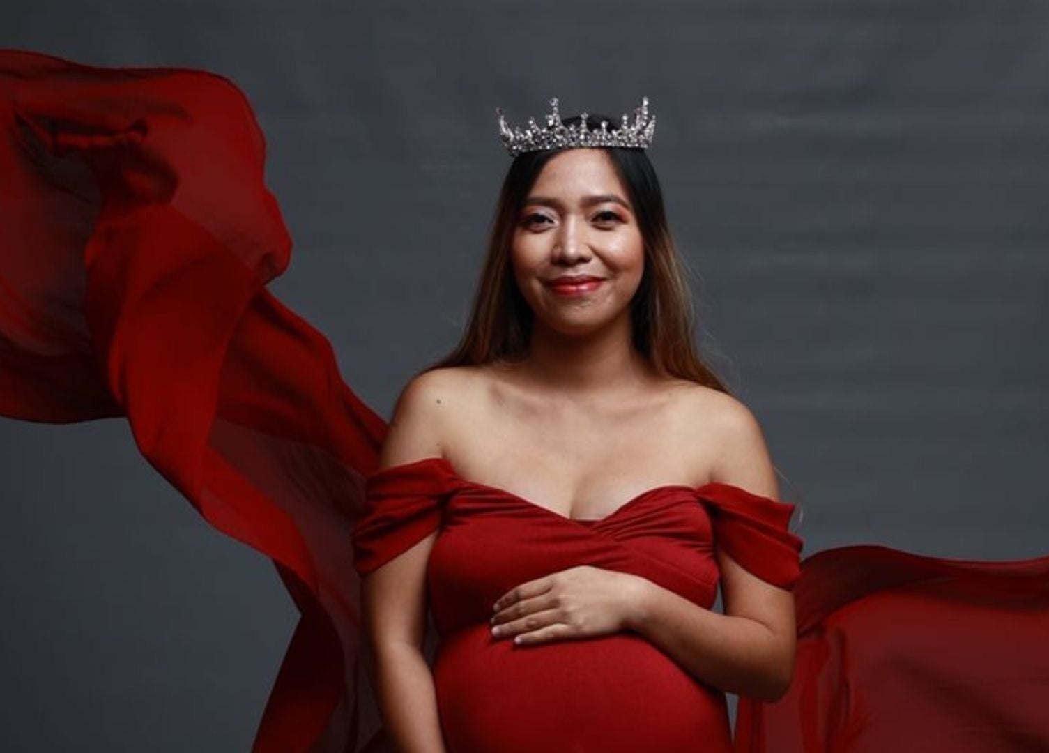 Pregnant woman in red gown and crown at Touched by Aljoy, Hammond Park, Western Australia, AU.