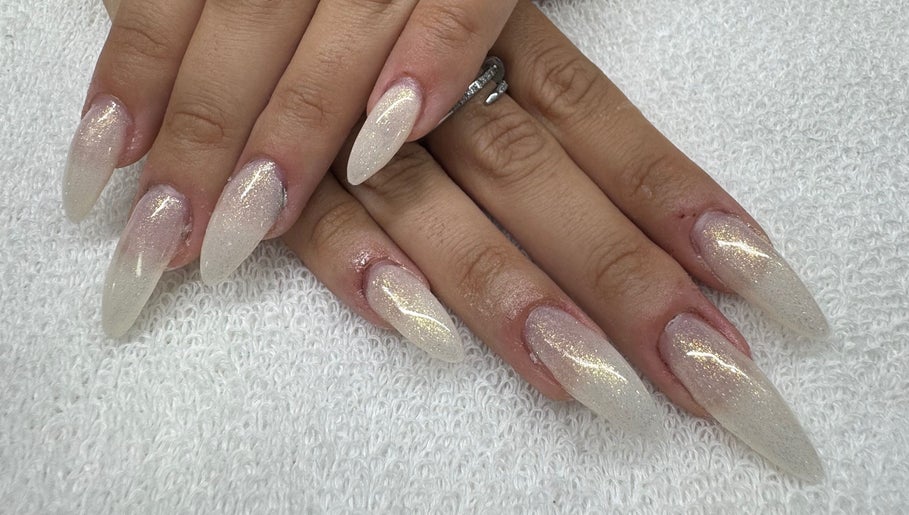 Elegant, glittery nail design at Golden Empire, Xgħajra, MT showcasing long, tapered tips.