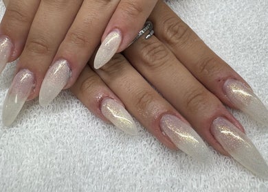 Elegant, glittery nail design at Golden Empire, Xgħajra, MT showcasing long, tapered tips.