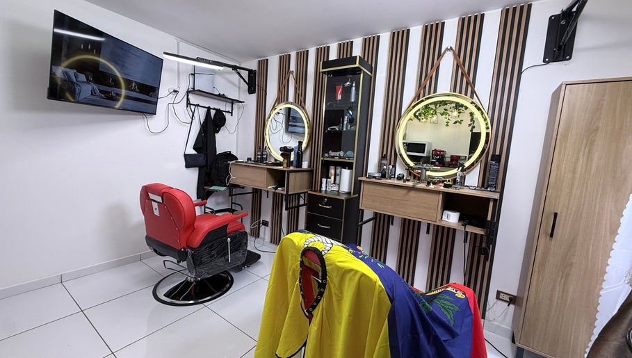 Interior moderno de MACCHIATO BARBERSTUDIO en Santiago De Surco, Provincia De Lima, PE, con sillón rojo icónico.