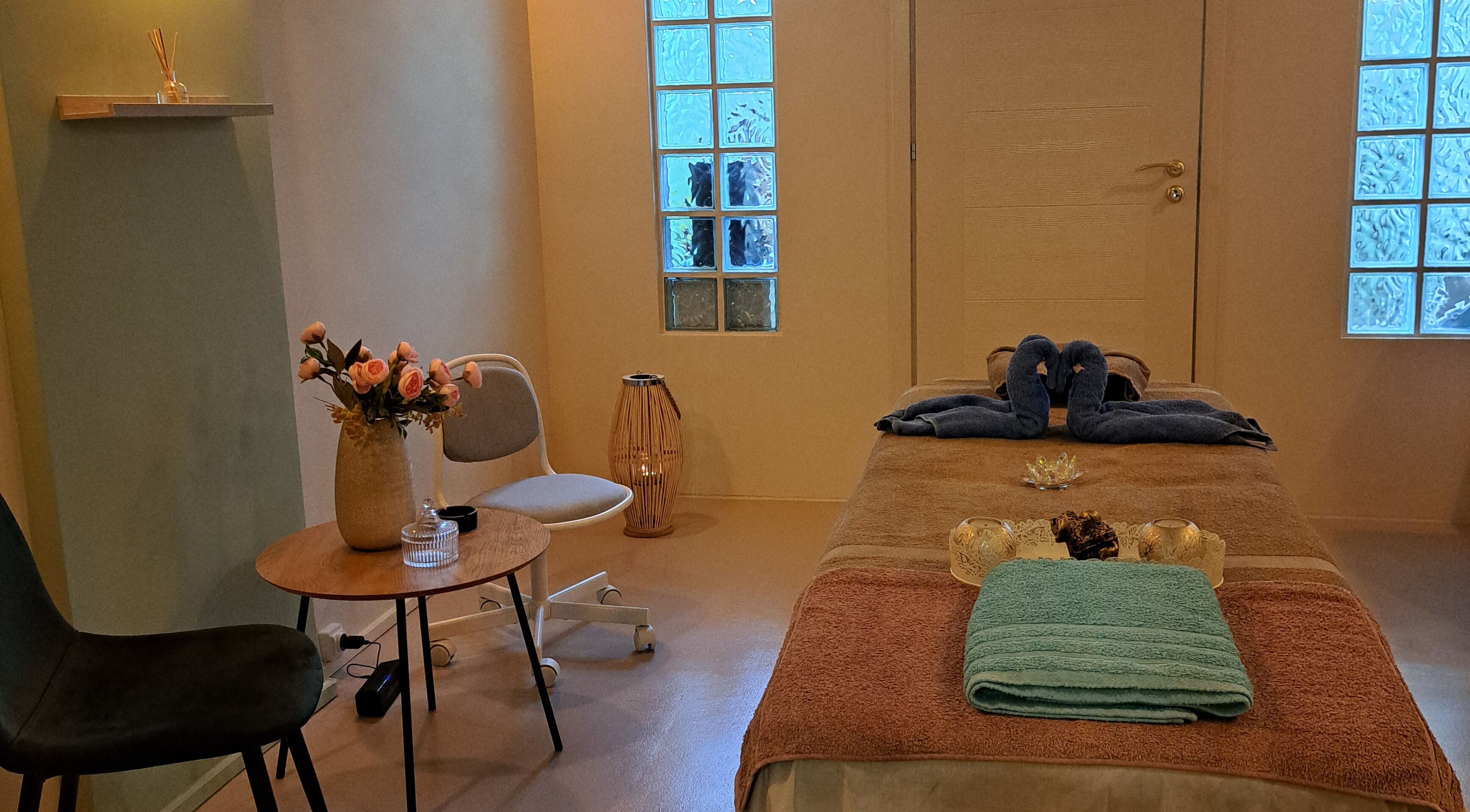 Δωμάτιο μασάζ στο Nirvana Massage And Beauty Spa, Χανιά, GR με κεριά και πετσέτα στο κρεβάτι.