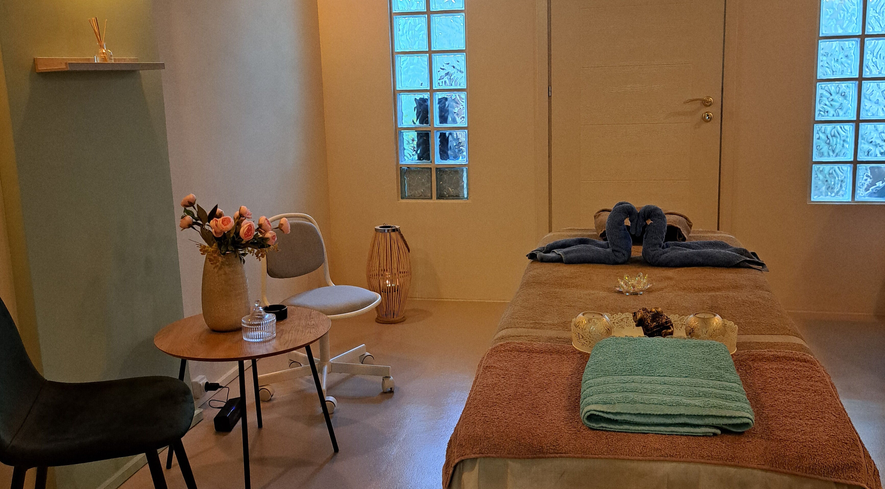 Δωμάτιο μασάζ στο Nirvana Massage And Beauty Spa, Χανιά, GR με κεριά και πετσέτα στο κρεβάτι.