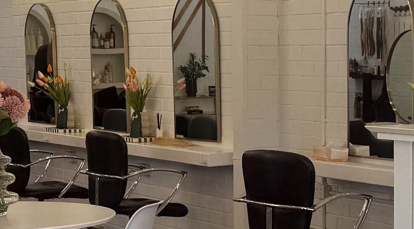 Sleek styling stations at NKD Hair Studio, Dianella, Western Australia, AU with modern mirrors and floral decor.