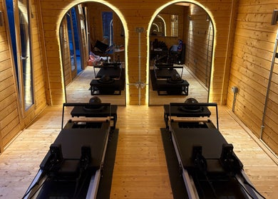 Pilates studio with reformers at The Reformama, Hoo, England, GB. Cozy wood-paneled design.