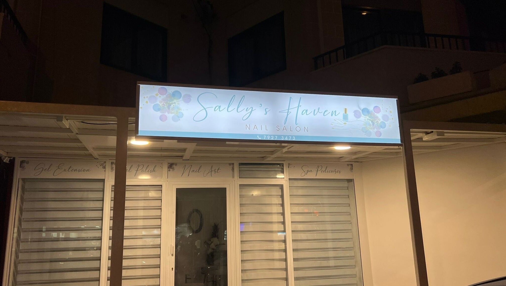 Ingresso del salone Sally’s Haven a San Pawl Il-baħar, MT, con insegna illuminata di notte.