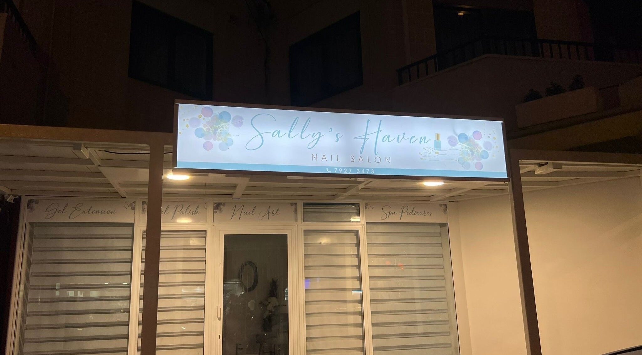 Ingresso del salone Sally’s Haven a San Pawl Il-baħar, MT, con insegna illuminata di notte.