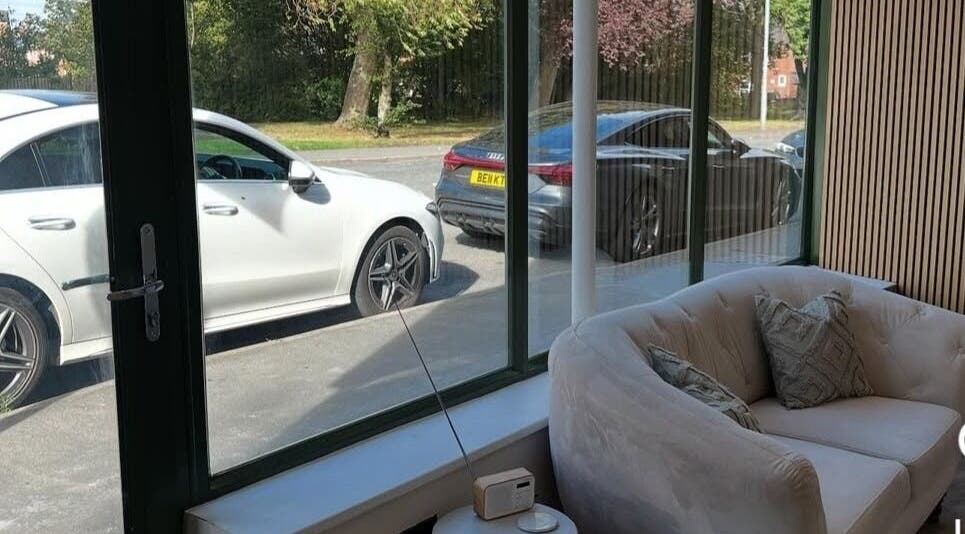 Cozy lounge area at Pro Brows.Studio in Normanton, England, GB with view of parked cars and greenery outside.