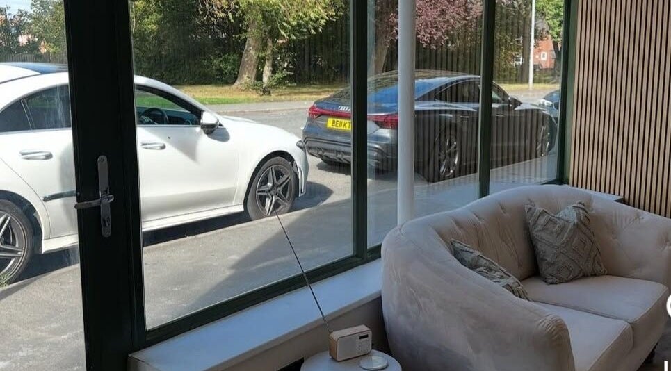 Cozy lounge area at Pro Brows.Studio in Normanton, England, GB with view of parked cars and greenery outside.