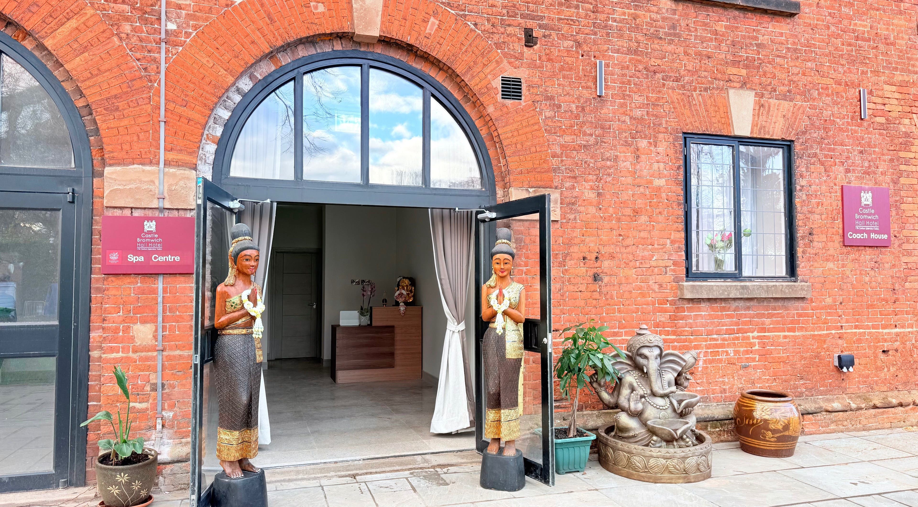 Entrance of Hannah Thai Spa in Birmingham, England, GB with traditional statues against red brick wall.