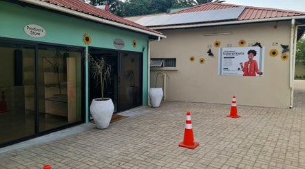 Entrance to Natural Kurls Rhodespark Branch, Lusaka, ZM. Features signage and decorative sunflowers.