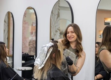Stylist at Moosh Hair Studio in Tweed Heads, NSW, AU, coloring client's hair with foil wrap.