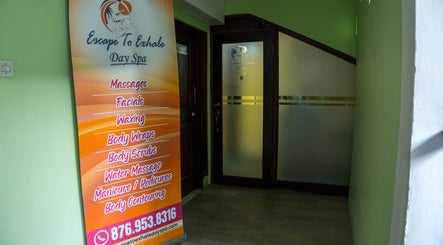 Entrance view of Escape To Exhale Day Spa in St. James Parish, JM with a service menu displayed.