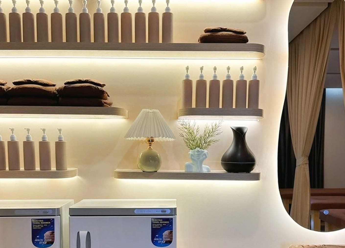 Cozy shelf setup at Léna Spa, Phu Quoc, Kiên Giang, VN, with bottles, towels, and elegant decor items.