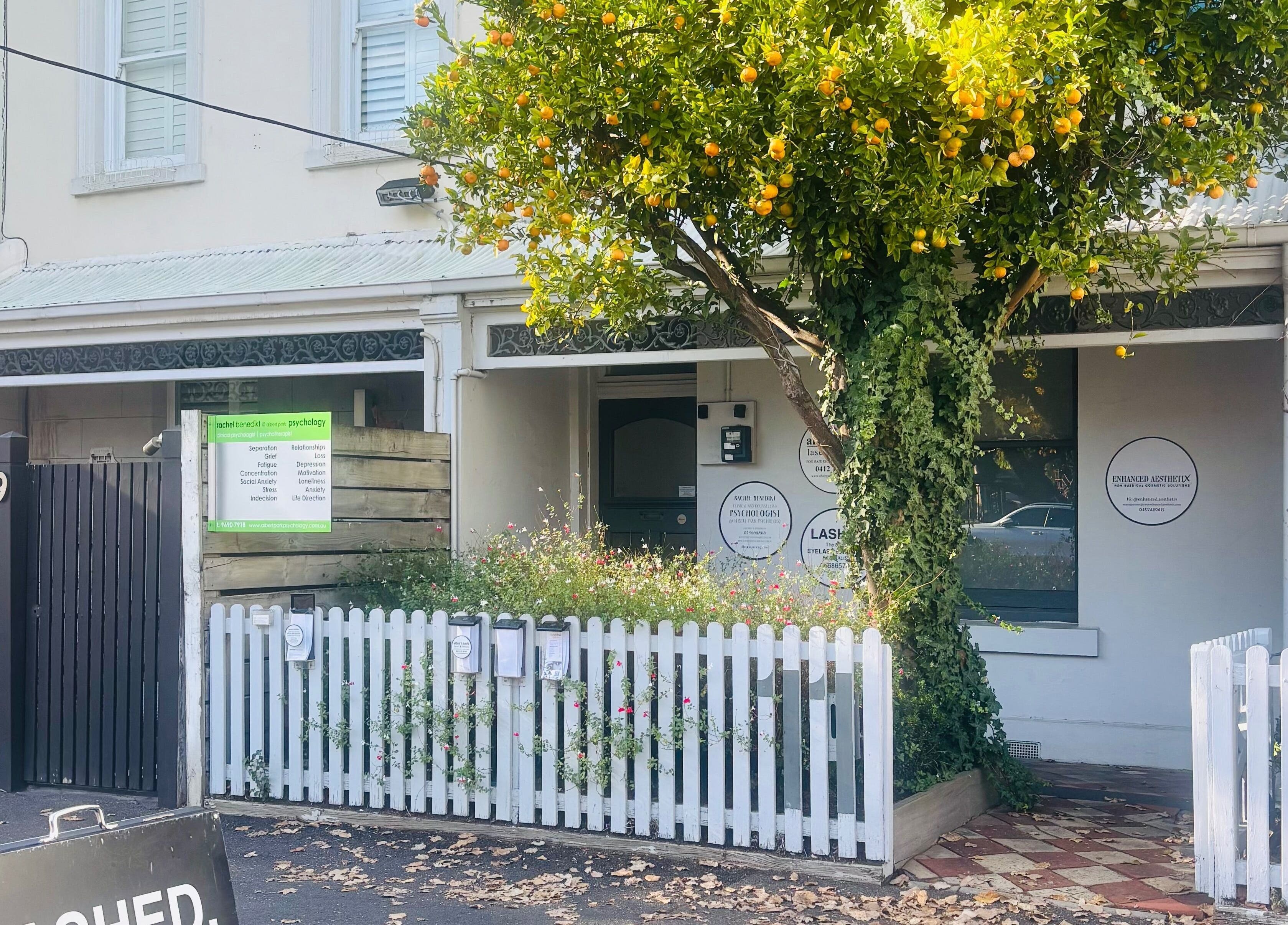 Exterior view of The GLOW UP Clinic (Albert Park) in Melbourne, Victoria, AU with charming picket fence and greenery.