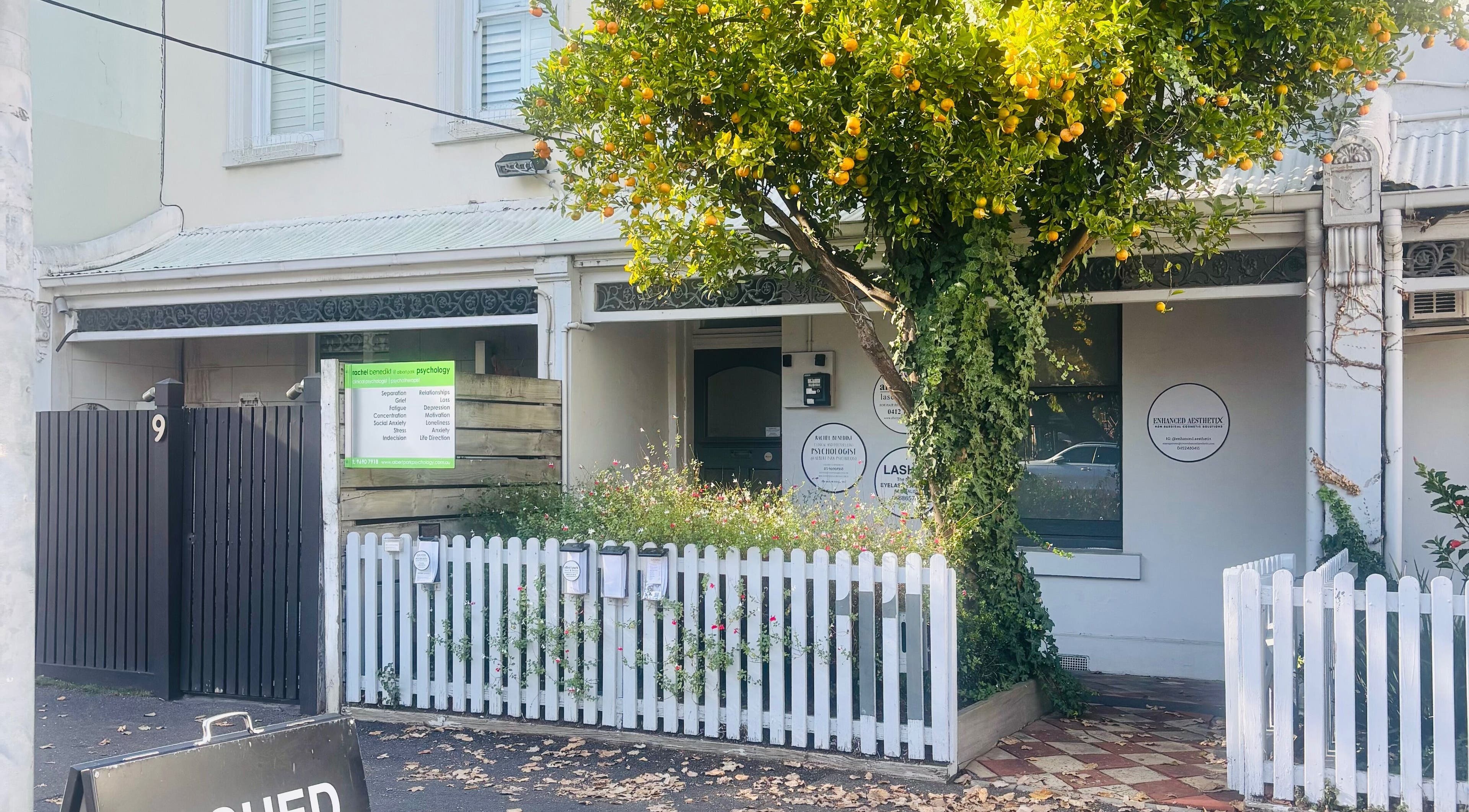 Exterior view of The GLOW UP Clinic (Albert Park) in Melbourne, Victoria, AU with charming picket fence and greenery.