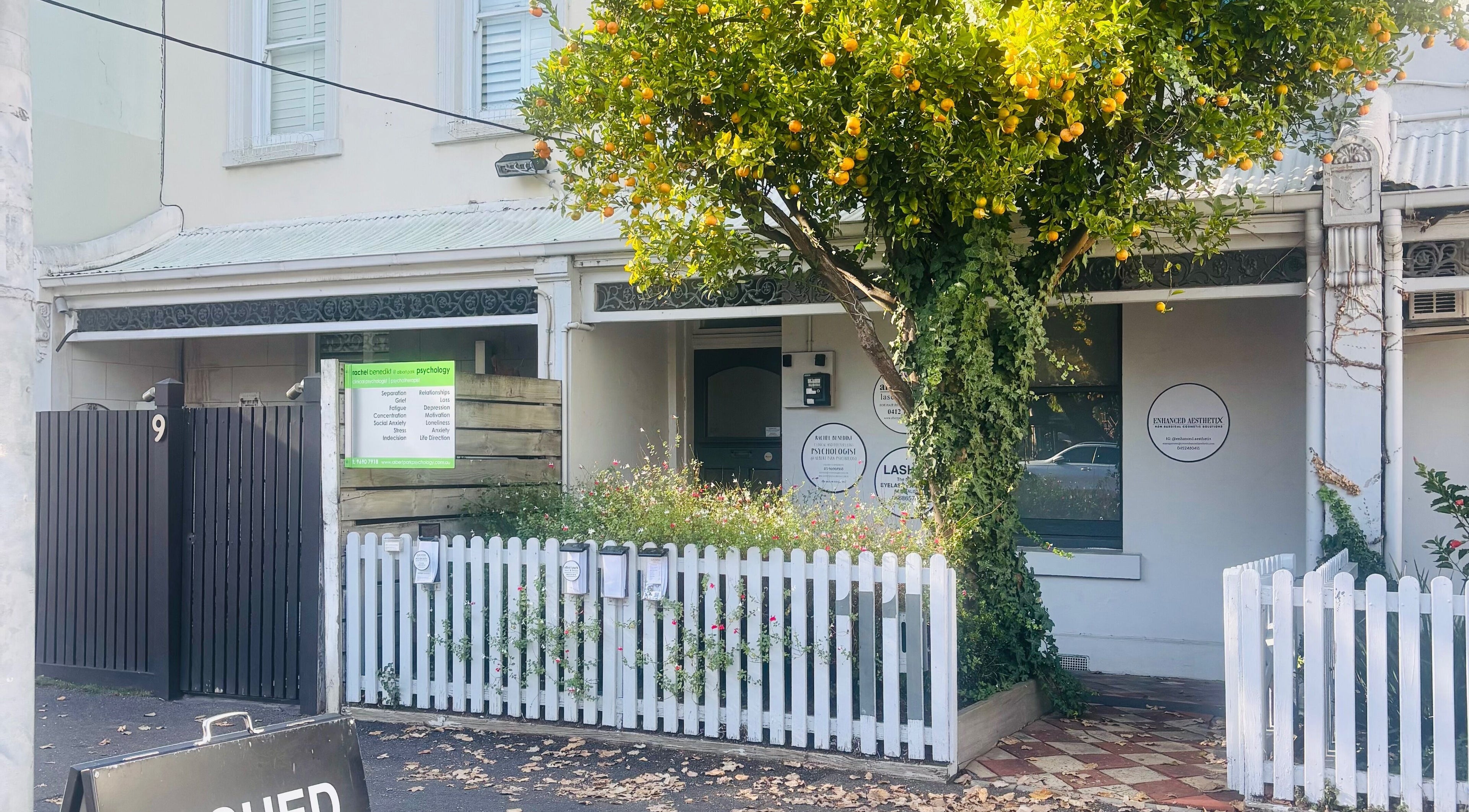 Exterior view of The GLOW UP Clinic (Albert Park) in Melbourne, Victoria, AU with charming picket fence and greenery.
