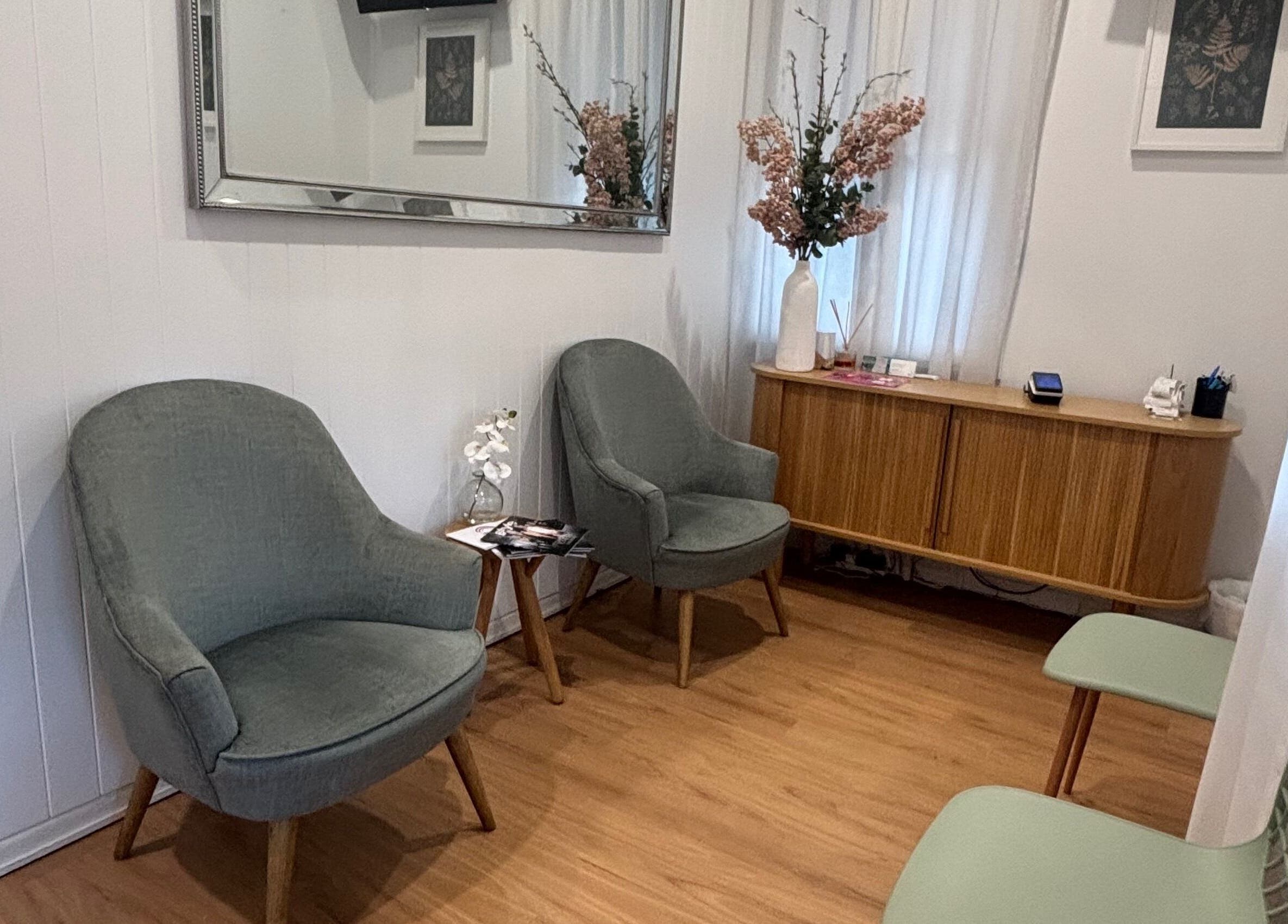 Inviting lounge at The GLOW UP Clinic (Brisbane) in Kangaroo Point, Queensland, AU with chic chairs and a floral touch.