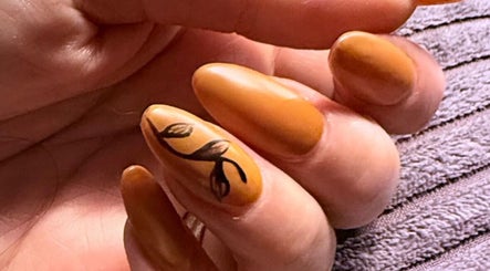 Detailed nail art design at Leigh & Rose, Flitwick, England, GB features intricate leaf pattern on orange nails.