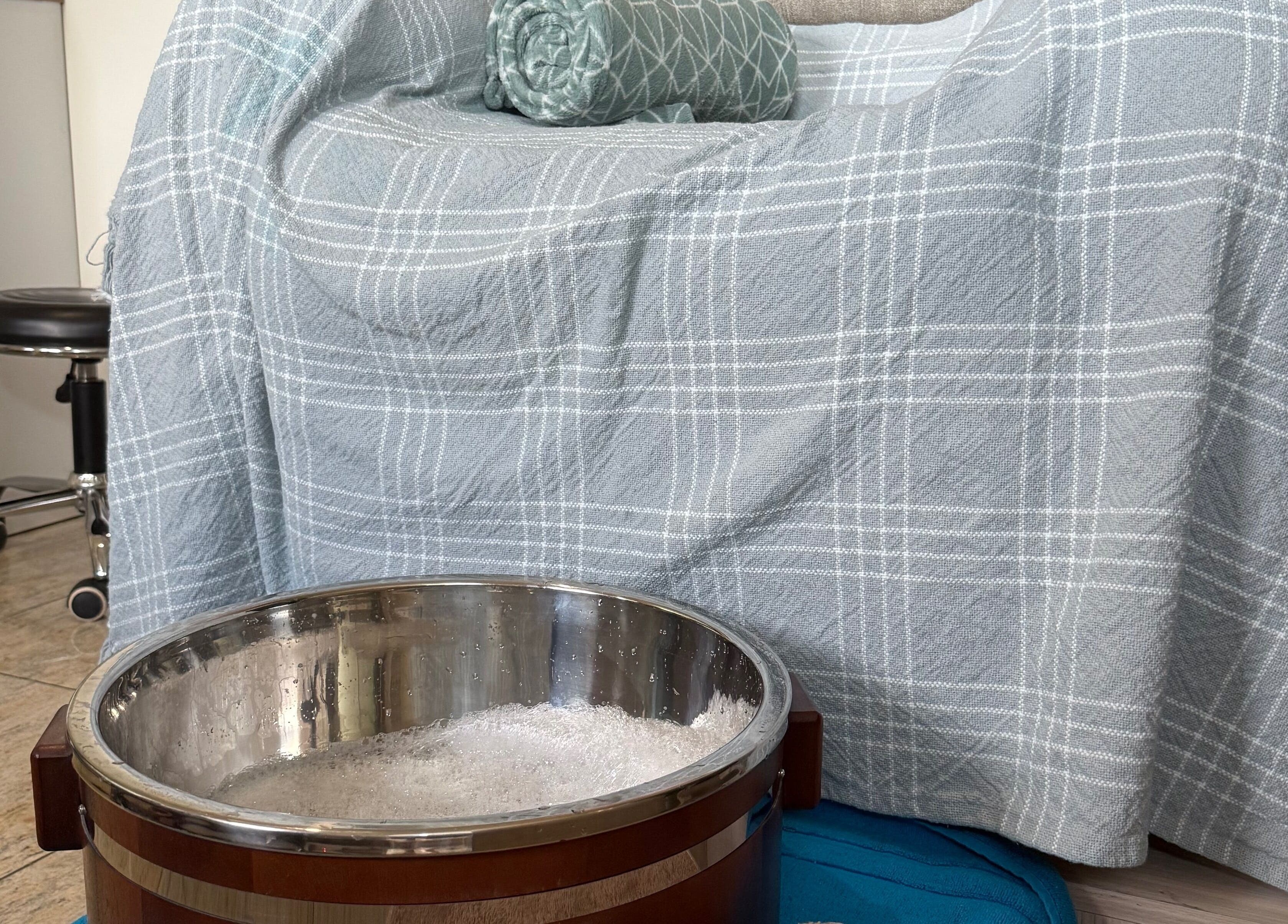 Relaxing foot soak setup at Be Still Spa, Roche Caiman, SC with a cozy blanket and patterned cushion.