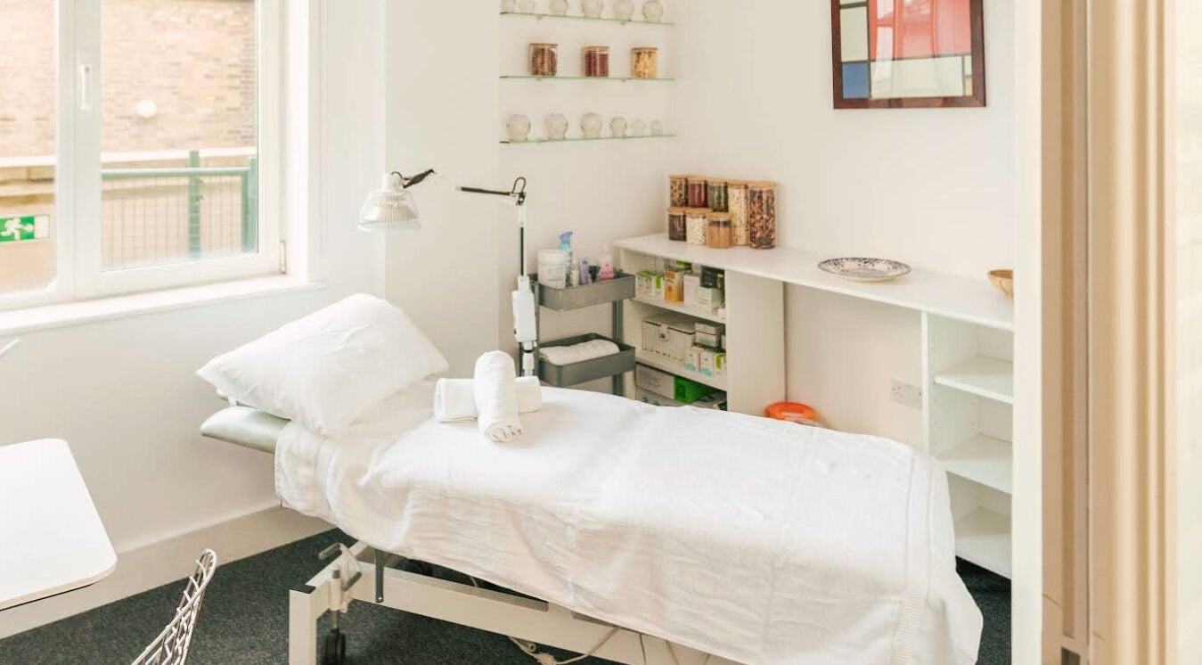 Relaxing treatment room at Omnia Lifestyle, London, England, GB featuring a bed and serene decor.