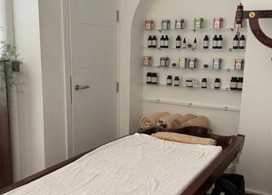 Relaxing treatment room at Omnia Lifestyle, London, England, GB, with massage table and herbal products.