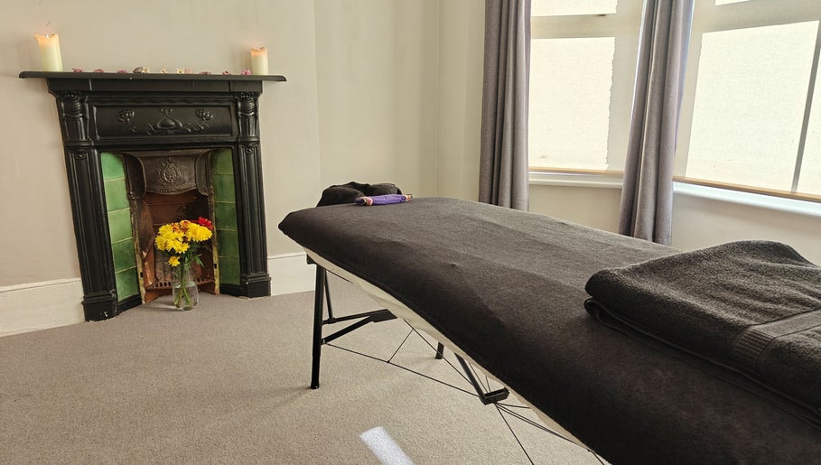 Relaxing massage room at Awaken Holistic Healing, London, England, GB with cozy fireplace and flowers.