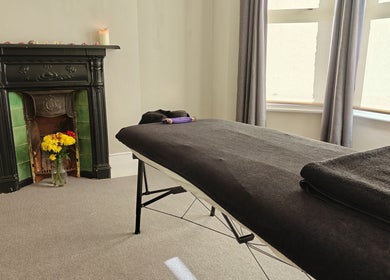 Relaxing massage room at Awaken Holistic Healing, London, England, GB with cozy fireplace and flowers.
