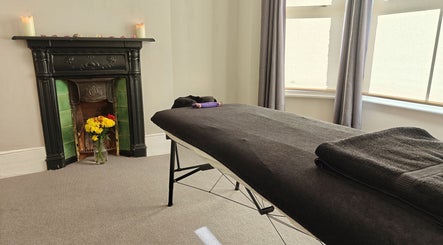 Relaxing massage room at Awaken Holistic Healing, London, England, GB with cozy fireplace and flowers.