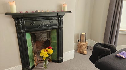 Cozy room at Awaken Holistic Healing in London, England, GB with candles and flowers on a vintage fireplace.