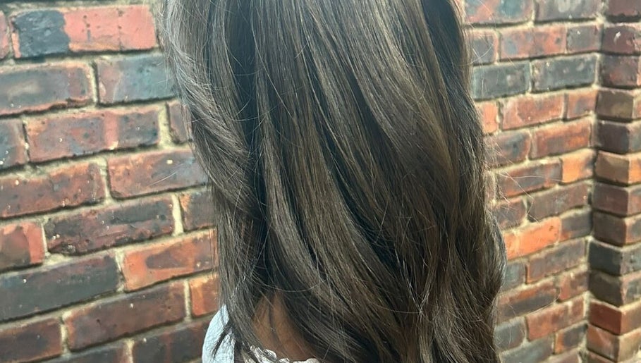 Stylish brown hair at ELEVATION HAIR 93 BY JULZ, Midrand, Gauteng, ZA, with a rustic brick backdrop.