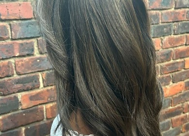 Stylish brown hair at ELEVATION HAIR 93 BY JULZ, Midrand, Gauteng, ZA, with a rustic brick backdrop.