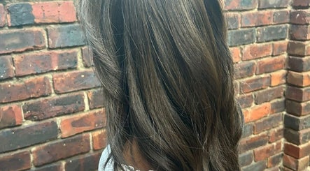 Stylish brown hair at ELEVATION HAIR 93 BY JULZ, Midrand, Gauteng, ZA, with a rustic brick backdrop.