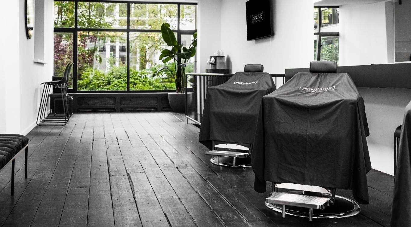 Modern barber chairs at MENSPIRE Old South, Amsterdam, Noord-Holland, NL with lush greenery outside.